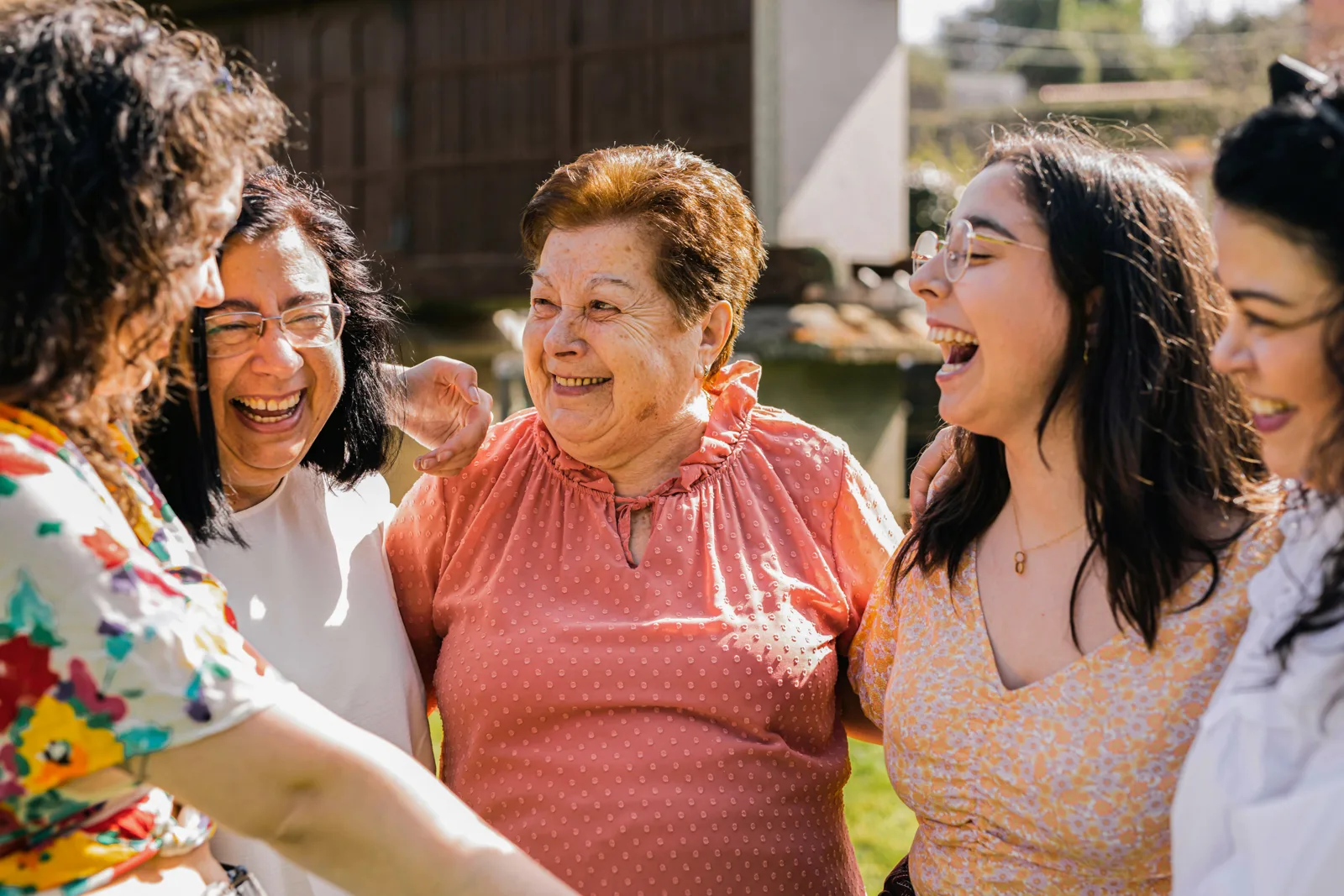 A grandmother laughing with the women of her family, arms around each other
