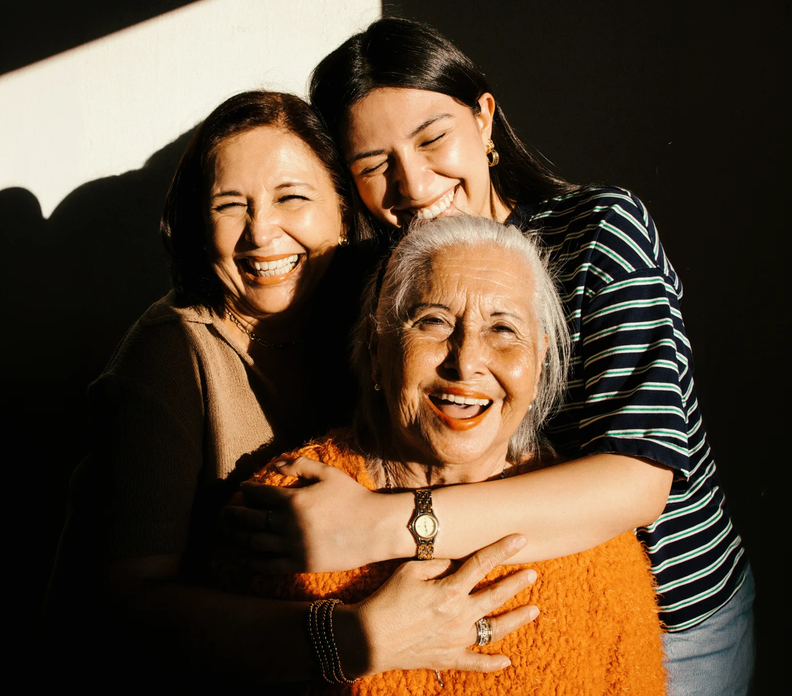 Three generations of women hugging and laughing