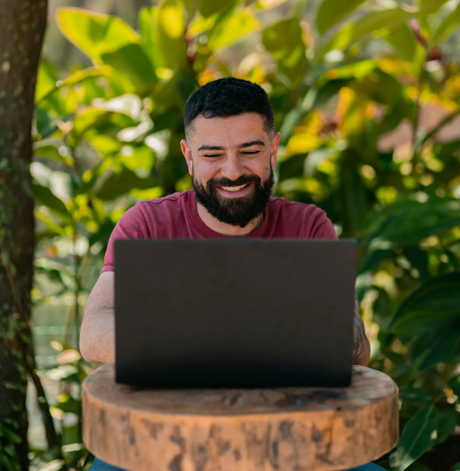 A smiling man using a laptop outdoors