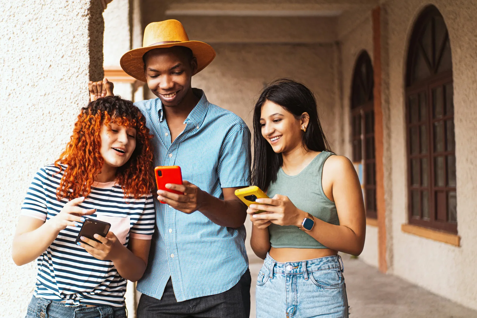 Three friends smiling at their phones together