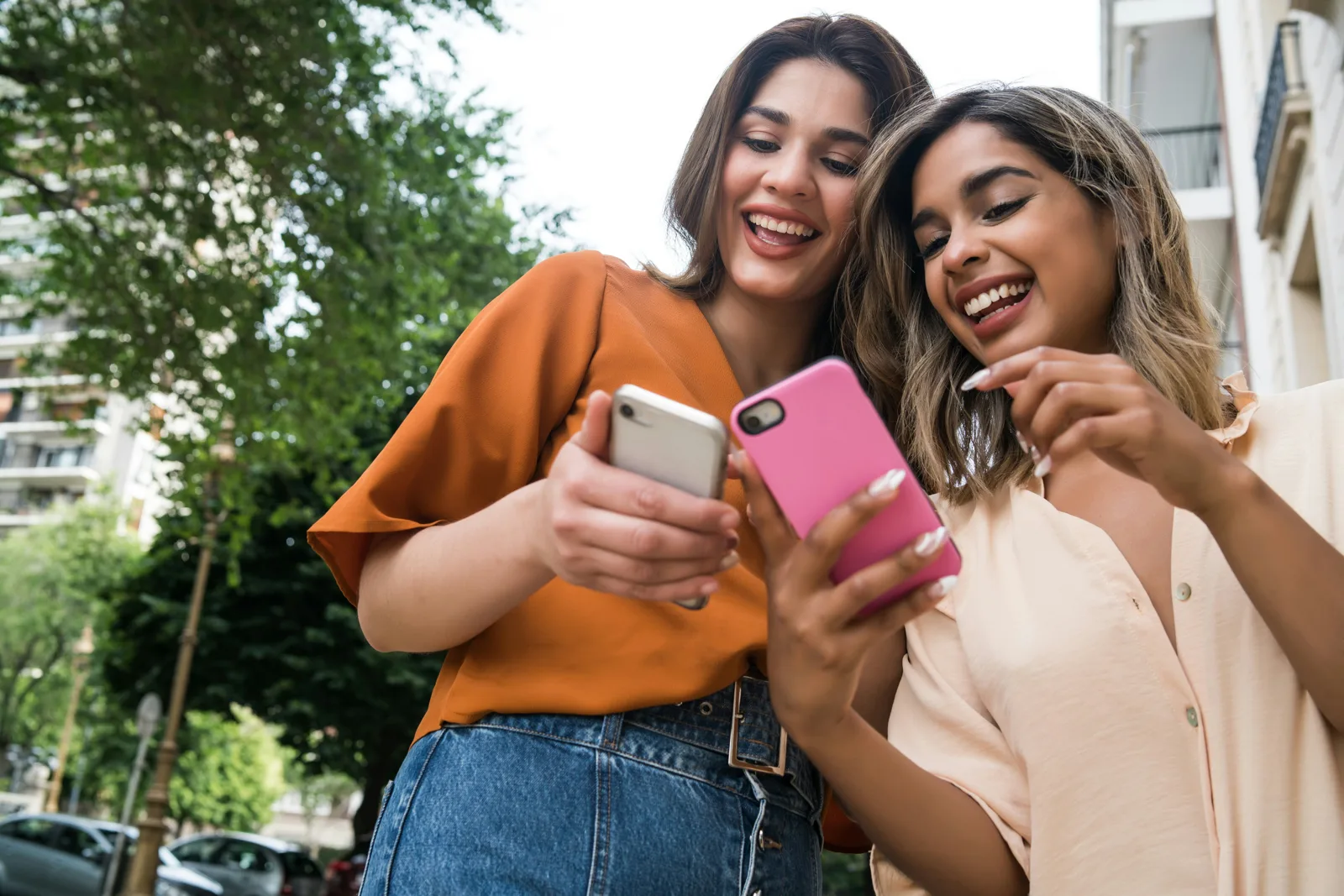 Two friends laughing as they look at their phones together